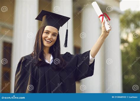 Happy Girl University Graduate Standing And Holding Diploma In Raised
