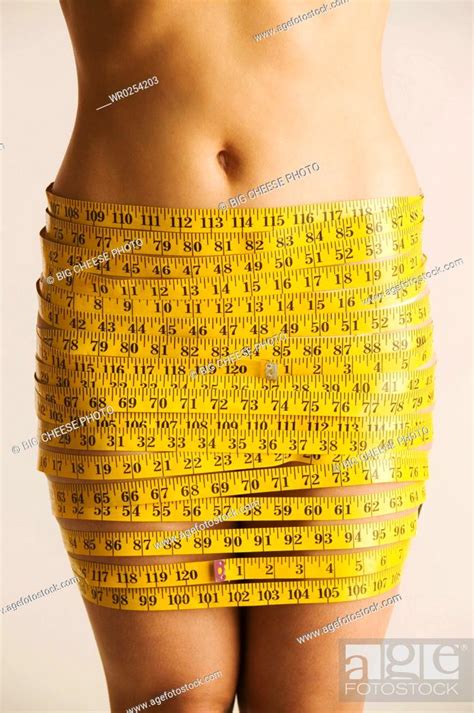 Midsection Of Nude Woman Wrapped In Measuring Tape Stock Photo