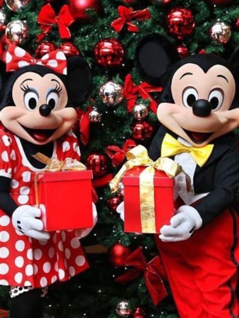 Two Mickey And Minnie Mouses Holding Presents In Front Of A Christmas