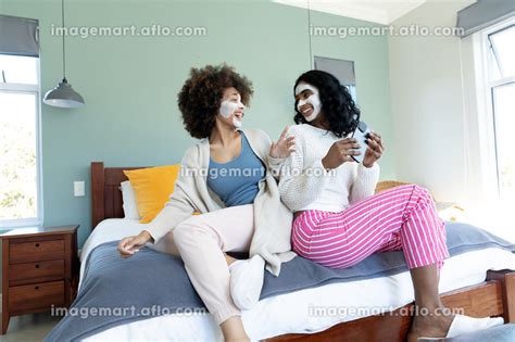 Biracial Cheerful Young Female Friends With Facial Creams On Faces