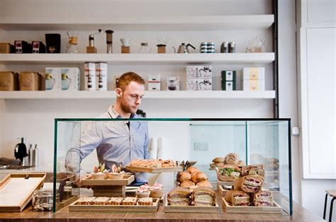 A Man Standing Behind A Counter Filled With Food
