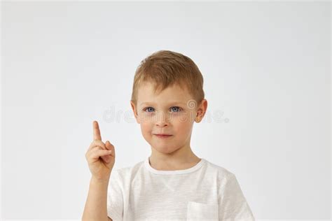 A Boy With A Funny Face Points His Finger Up On A White Background