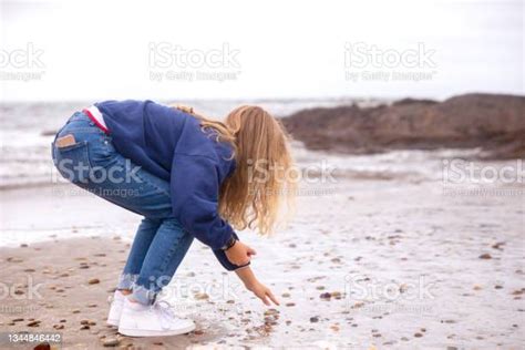 Teenager Picking Up Pebbles At The Beach Stock Photo Download Image