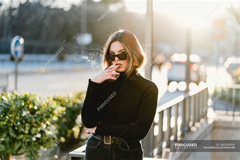 Stylish Woman Smoking Cigarette Near Metro Station On Sunny Street