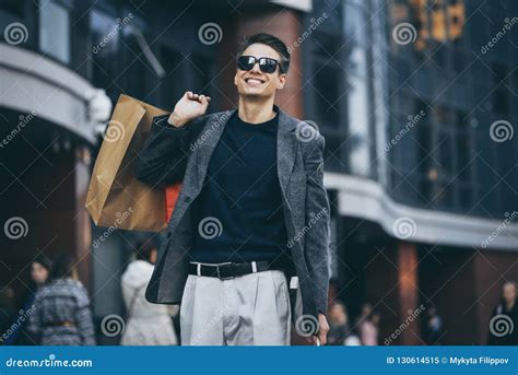 Serious Stylish Young Man With Sunglasses Walking In Urban Street And