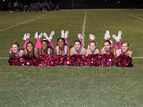 A Group Of Cheerleaders Posing For A Photo On The Sidelines At Night