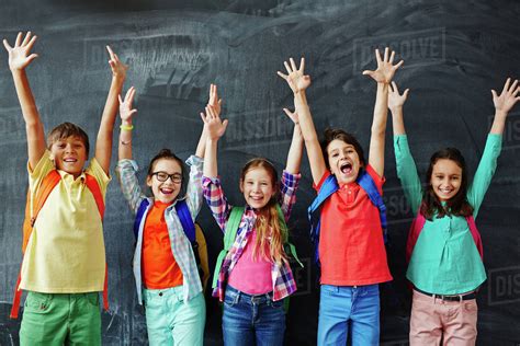 Excited Schoolchildren Standing With Hands Up Stock Photo Dissolve