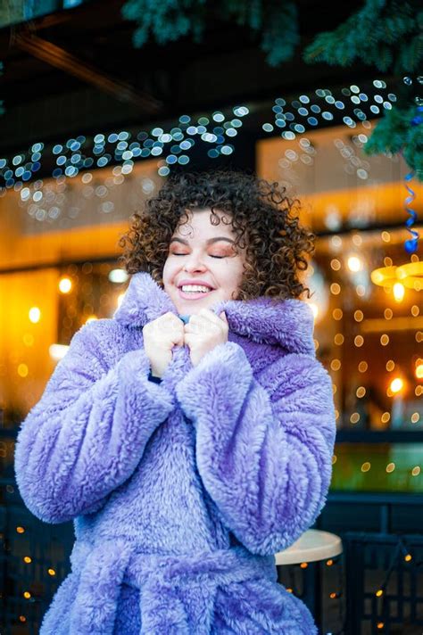 Curly Haired Woman In Trendy Violet Coat Drinks Mulled Wine Outdoors