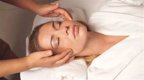 Pretty Woman Lies With Her Eyes Closed In The Spa And Enjoys A Facial Massage Stock Image
