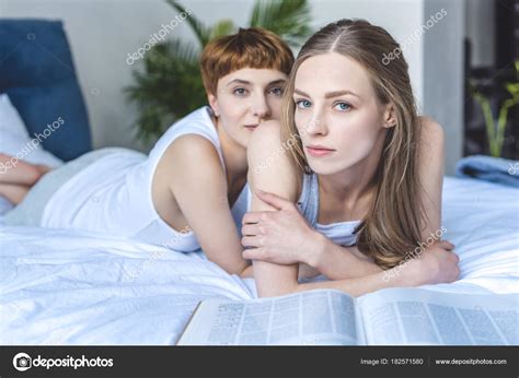 ベッドで美しい若いレズビアンのカップル Emracing ストック写真 VikaOvcharenko 182571580