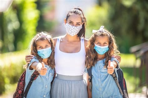 una madre y su hija gemela usan una máscara protectora cuando regresan a la escuela durante la