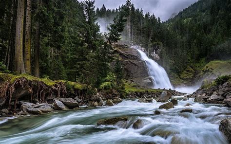 Waterfalls Pouring On River Between Trees Covered Forest Mountains