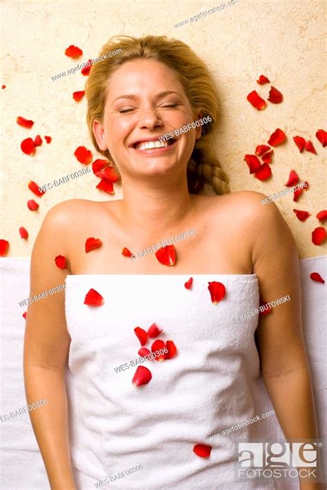 Germany Young Woman Lying On Massage Table Petals On Chest Stock