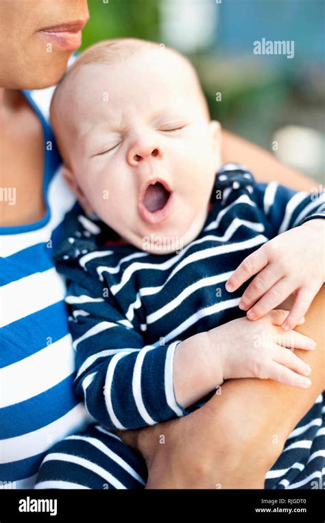 Mother Holding Yawning Baby Boy Stock Photo Alamy