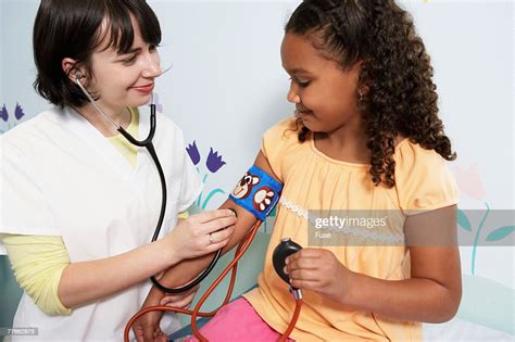 Nurse Taking Girls Blood Pressure At Clinic High Res Stock Photo