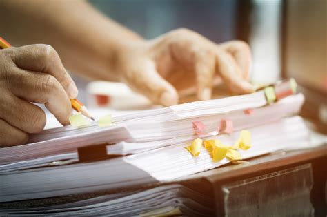 Businessman Hands Holding Pencil Working In Stacks Of Paper Files