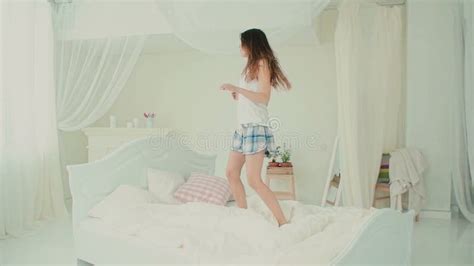 Happy Young Woman Wearing Pajamas Jumping On Her Bed Brunette Girl