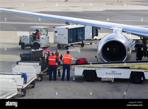 Baggage Handlers Loading Luggage Onto A Convey Into An Airplane On