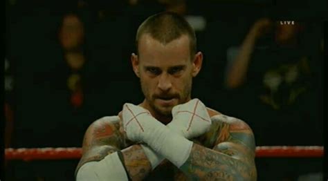 A Man With Tattoos On His Arms Standing In Front Of A Boxing Ring