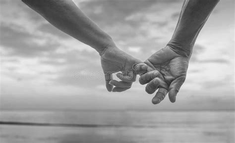 close up hand of senior couple hook each other s little finger together near seaside at the