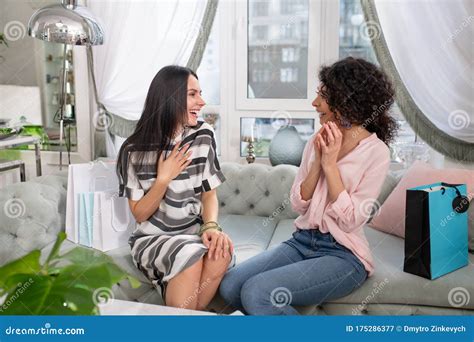 Two Dark Haired Women Talking While Sitting On The Sofa Stock Image