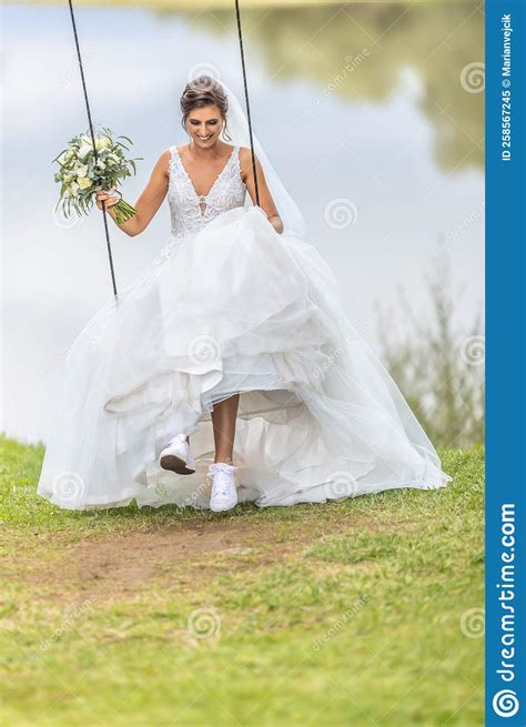 Hapy Bride Swings On A Swing And Laughs Holding Wedding Bouquet In Her Hand Stock Image Image