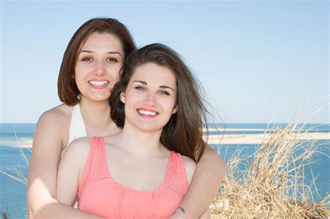 tersenyum gadis pasangan lesbian memegang memeluk satu sama lain di pantai pantai foto stok