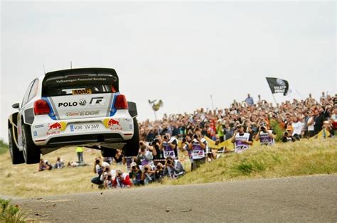 A Rally Car Flying Through The Air In Front Of A Crowd