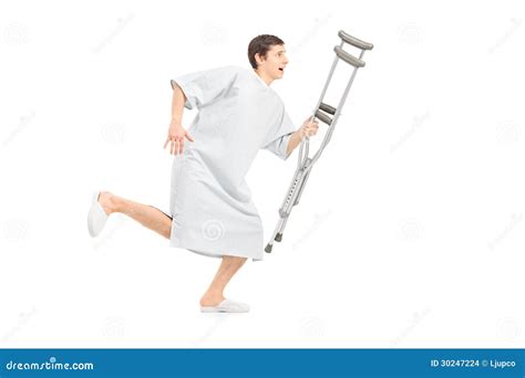 Full Length Portrait Of A Male Patient Running And Holding A Crutch