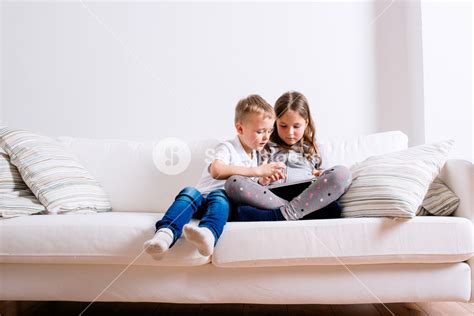 Children Enjoying Screen Time Together On A Cozy Sofa Royalty Free