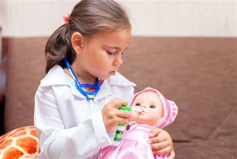 Cute Child Girl Playing Doctor With Baby Doll Toy Stock Photo Image
