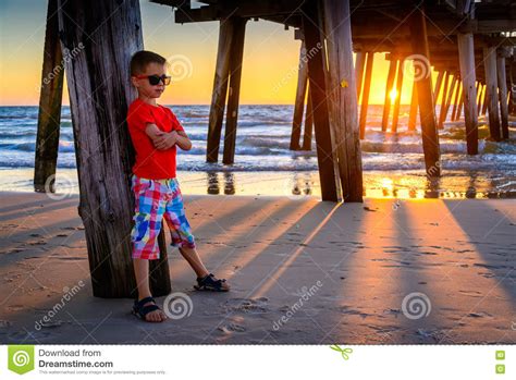 Pensive sad boy under a tree. Boy Standing On The Beach Under Pier At Sunset Stock Photo ...