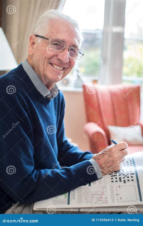 Portrait Of Senior Man Doing Crossword Puzzle At Home Stock Photo