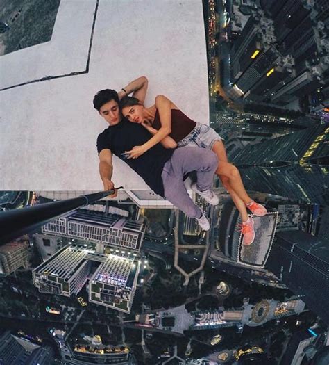 Two People Laying On Top Of A Tall Building