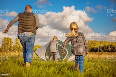 Handsome Redhead Father And Blonde Daughters Chasing A Tent Caught In The Wind On A Camping
