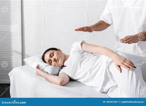 View Of Healer Standing Near Sleeping Woman And Holding Hands Over Her