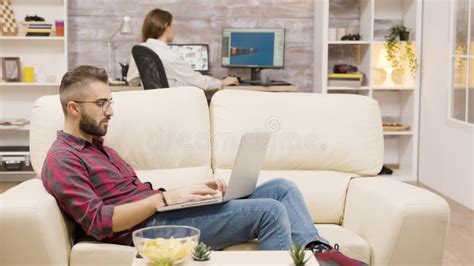 Handsome Freelancer Working On Laptop While Sitting On The Couch Stock