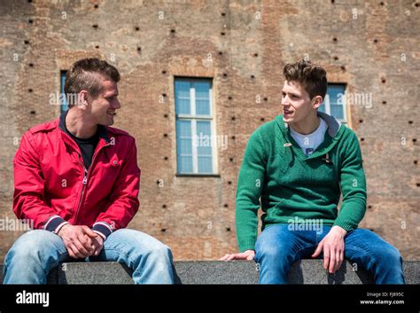 Two Young Men Talking While Sitting On Curb Summertime Stock Photo Alamy