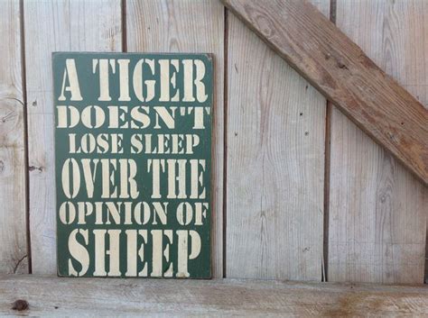 a green sign that says a tiger doesn t lose sleep over the opinion of sheep
