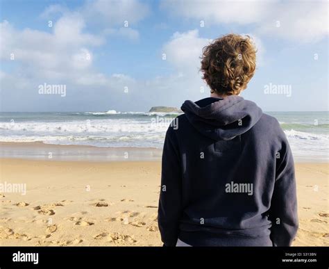 Teenage Boy Standing On A Beach Looking Out To Sea Stock Photo Alamy