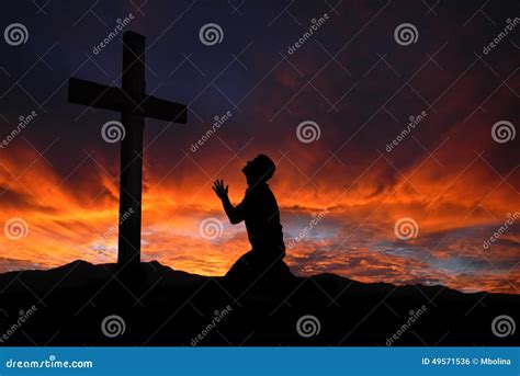 Silhouette Of Man Praying To A Cross With Heavenly Cloudscape Sunset