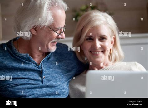 Loving Senior Husband In Glasses Looking At Smiling Middle Aged Wife