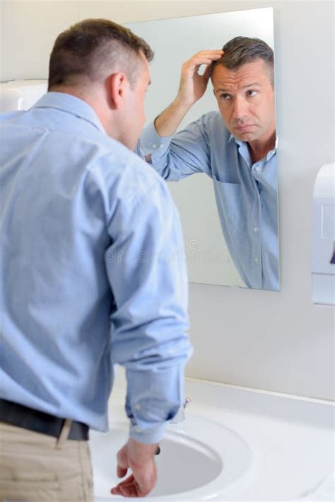 Hombre Que Mira El Pelo En Espejo Imagen De Archivo Imagen De Espejo