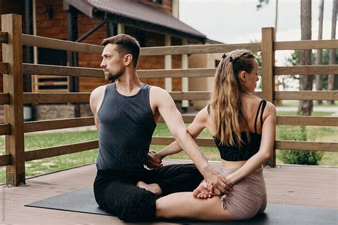 Pair Practice Yoga Together Man And Woman Holding Hands And Makes Twist By Stocksy