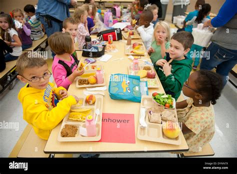 Elementary School Children Sitting At Tables Having Lunch In A