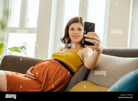 Pregnant Woman Taking A Selfie With Smartphone On Her Couch At Home
