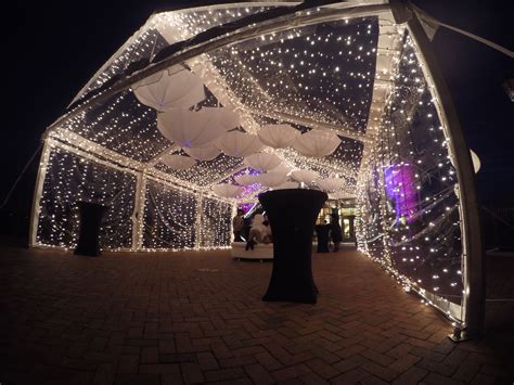 An Outdoor Tent Covered In Lights And Umbrellas
