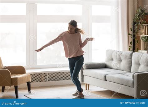 Full Length Of Active Young Woman Dancing In Living Room Stock Photo
