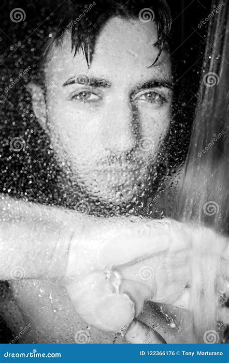 Hunky Handsome Man Male With Beard And Muscular Arms Is Wet In Shower Looking At Camera