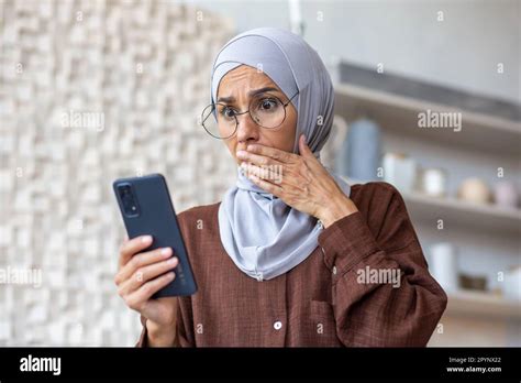 Junge Araberin Im Hijab Die Zu Hause In Der Küche Schockiert Auf Ein Telefon Schaut Sie Hielt
